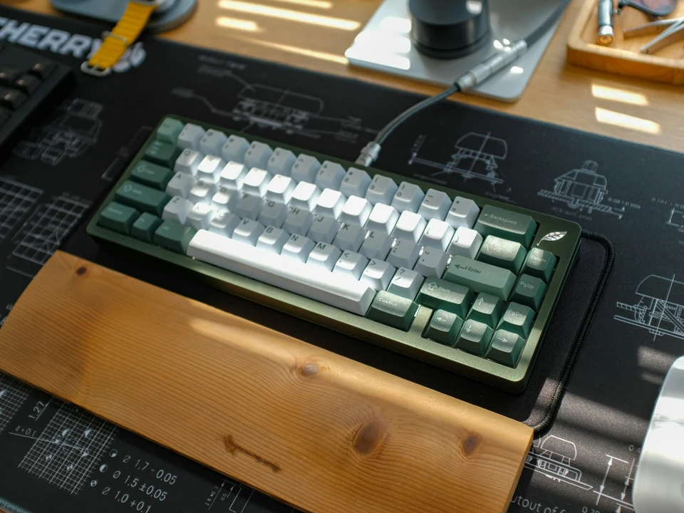 Compact mechanical keyboard with white and green keycaps on a desk mat