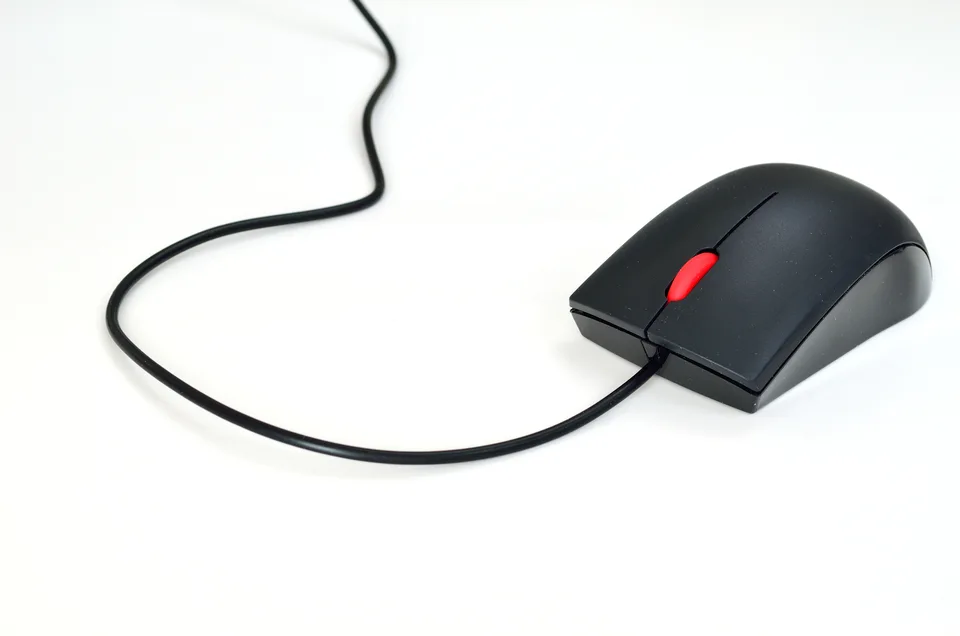 Black wired computer mouse with a red scroll wheel on a white surface