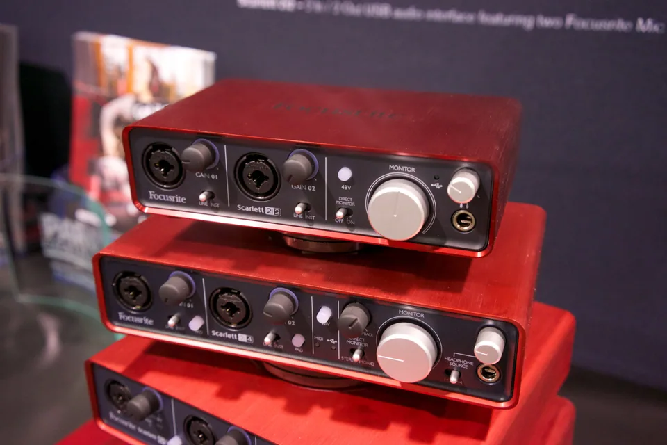 Three red Focusrite Scarlett USB audio interfaces stacked at a trade show